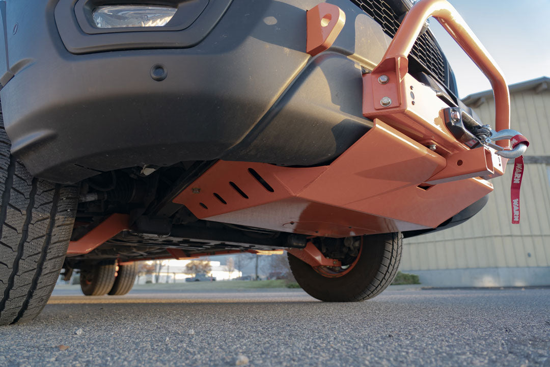 Close-up of the adjustable high clearance lower control arm for Ford Transit AWD and RWD, showing tire and suspension components for optimal camber adjustment and performance.