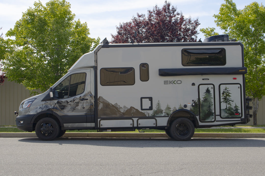 White RV parked roadside, showcasing the OPTI-RATE REPLACEMENT LEAF SPRINGS for TRANSIT (PAIR), designed for adjustable spring rate and ride height tuning.