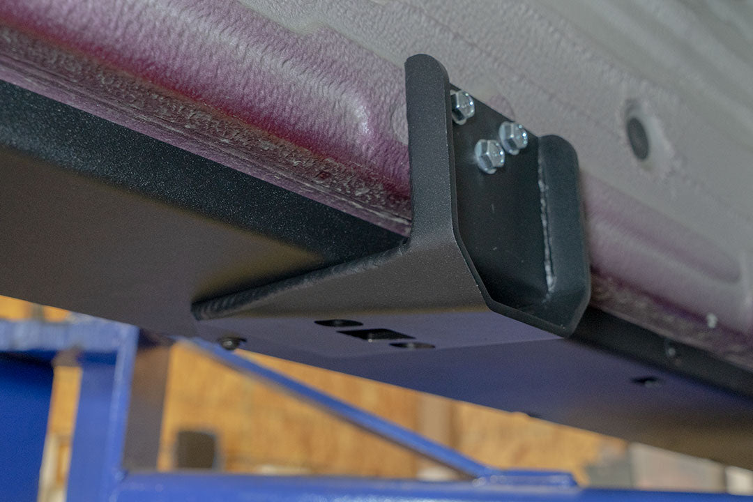 Rocker Guards - Sprinter AWD (2023+ 144 Wheelbase Only) by Van Compass: Close-up of metal bracket with bolts and screws, showcasing sturdy construction for van chassis reinforcement.