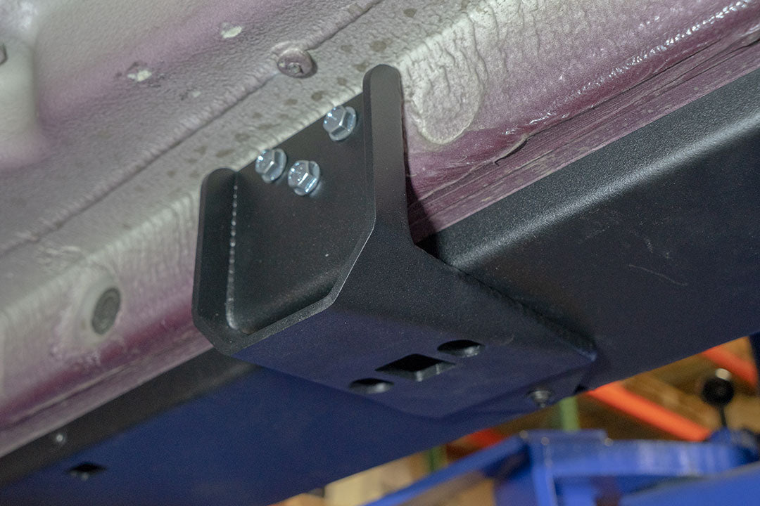 Rocker Guards - Sprinter AWD (2023+ 144 Wheelbase Only) by Van Compass: Close-up of metal bracket with bolts and screws, showcasing sturdy construction for van chassis reinforcement.