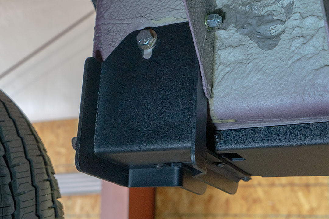 Rocker Guards - Sprinter AWD (2023+ 144 Wheelbase Only) by Van Compass: Close-up of metal bracket with bolts and screws, showcasing sturdy construction for van chassis reinforcement.
