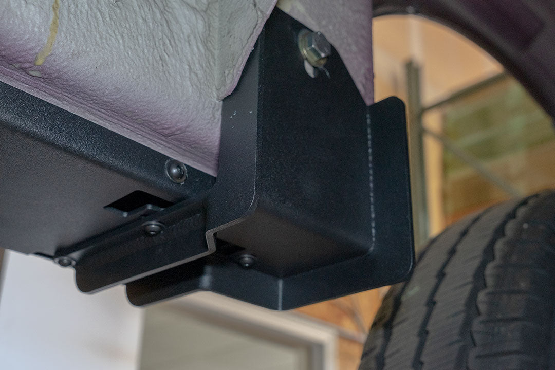 Rocker Guards - Sprinter AWD (2023+ 144 Wheelbase Only) by Van Compass: Close-up of metal bracket with bolts and screws, showcasing sturdy construction for van chassis reinforcement.