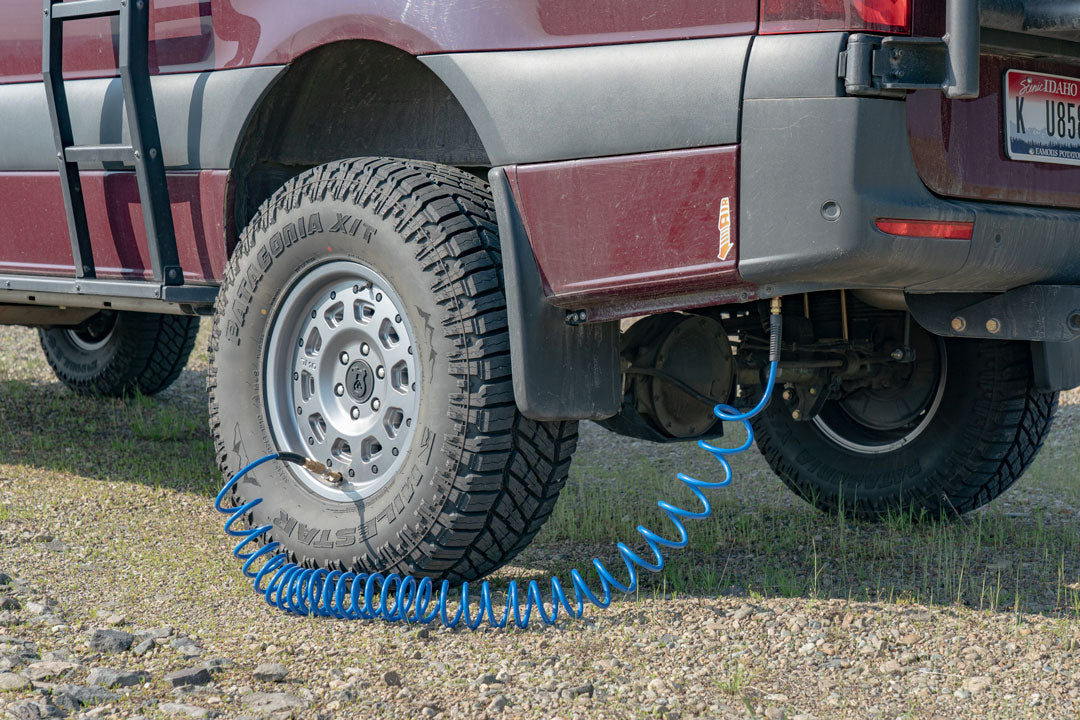 Close-up of the ON BOARD AIR SYSTEM AIRLINE KIT - Sprinter 2019+ by VAN COMPASS, showing the tire with a blue hose attached for inflating tires.