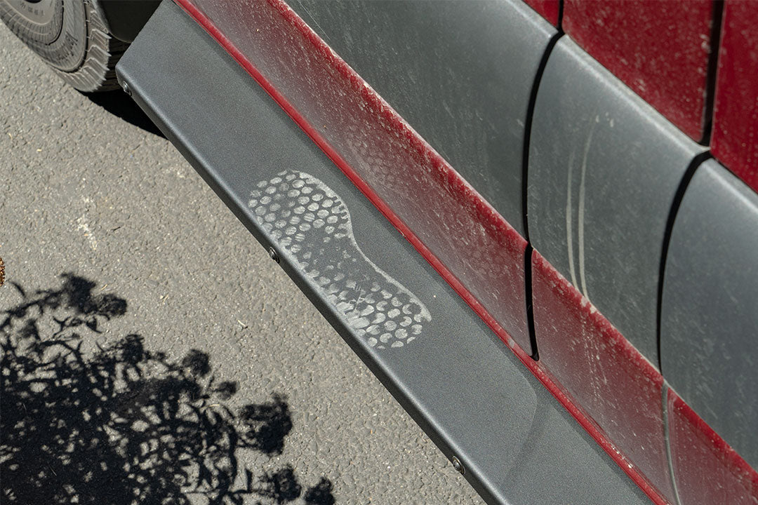 Close-up of Van Compass Rocker Guards on a car, showing a shoe print on the robust steel surface designed for Sprinter AWD 144 wheelbase.