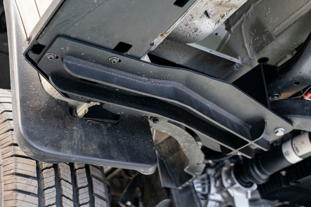 Rocker Guards - Sprinter AWD (2023+ 144 Wheelbase Only) by Van Compass: Close-up of metal bracket with bolts and screws, showcasing sturdy construction for van chassis reinforcement.