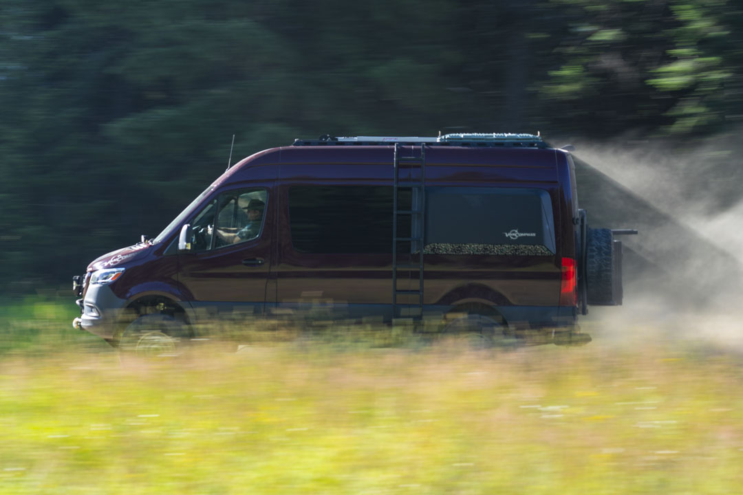 FALCON 3.3 Fast Adjust Inverted Rally Strut by Van Compass for Sprinter 4x4 and AWD, 2015-Present. A van driving through a field, showcasing suspension performance.