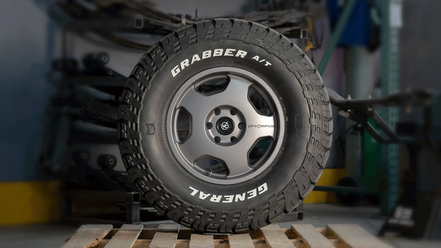 Animated rotating view of the Van Compass CHUNK 17” alloy wheel mounted with a General Grabber A/T tire, showcasing its rugged five-spoke design and bold stance against a garage backdrop