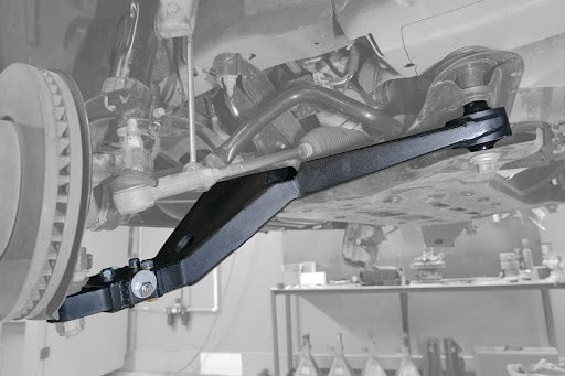 Close-up of the ADJUSTABLE HIGH CLEARANCE LOWER CONTROL ARM for Ford Transit, showcasing its precision cam bolt and robust, high-clearance design for optimized performance and tire life.