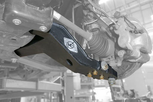 Close-up of the Adjustable High Clearance Lower Control Arm for Ford Transit (2020-Present), showcasing the suspension layout and precision cam bolt set for camber adjustment.