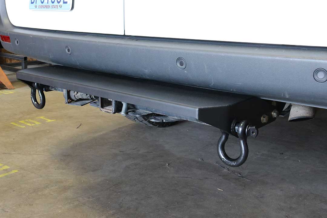 REAR MINI TUG STEP - SPRINTER (2019+) by VAN COMPASS attached to vehicle's rear hitch, featuring a durable metal step with D-ring shackle points for recovery.