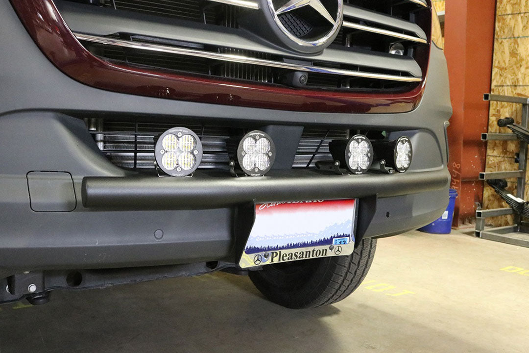 Front view of a car with the Van Compass Front Step Light Bar for Sprinter (2019+), showcasing mounted auxiliary lights and preserved step functionality.