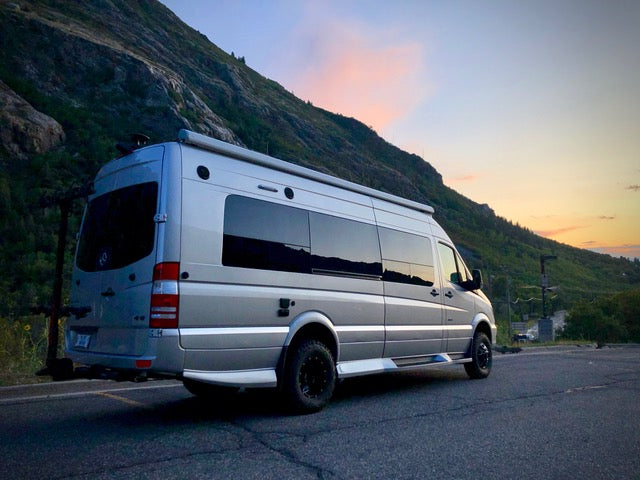 Silver van equipped with the Stage 3 Opti-Rate Dually System by Van Compass, parked roadside, showcasing enhanced suspension and stability features for heavy vans.