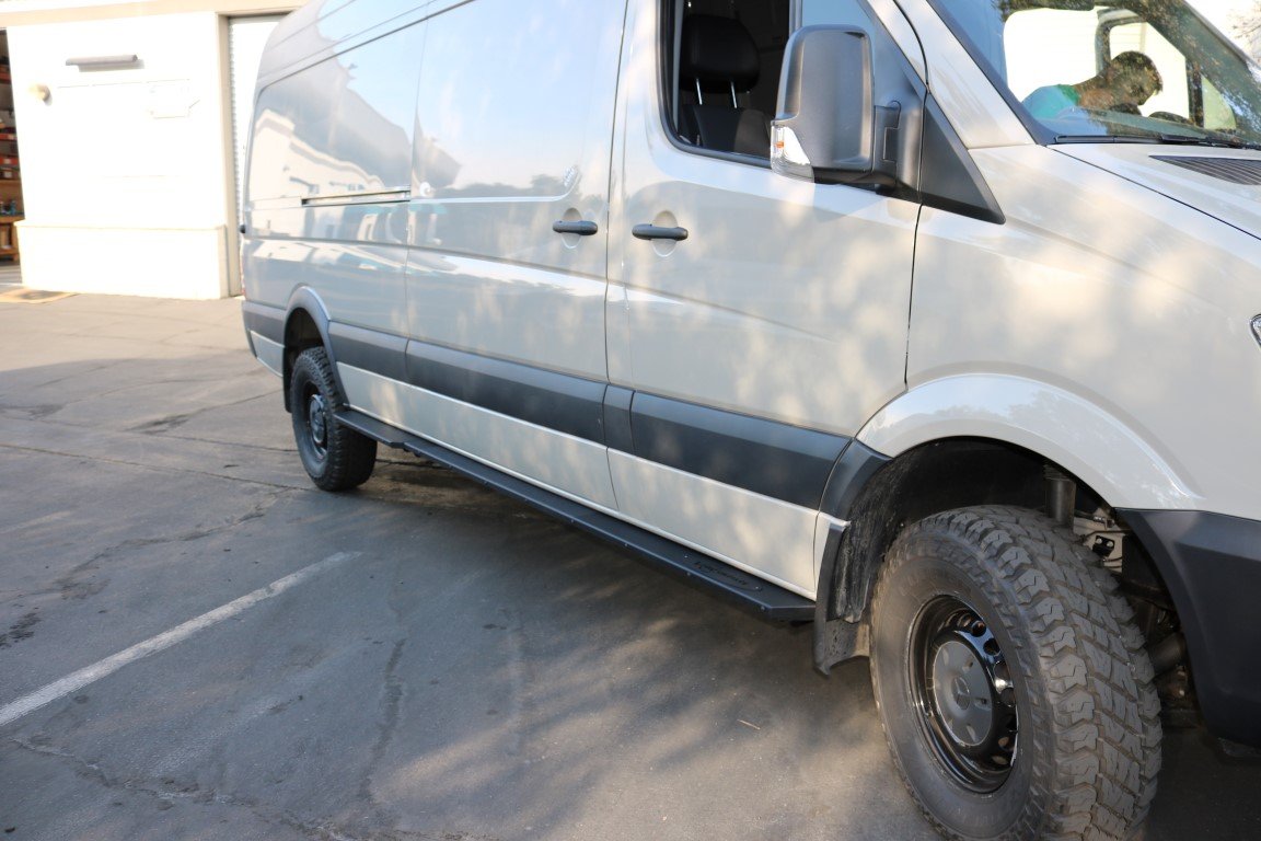 Rocker Guards - Sprinter 4x4 (2015-2022 170 Wheelbase Only) by Van Compass, showing a white van with emphasis on robust side steps and tire protection.