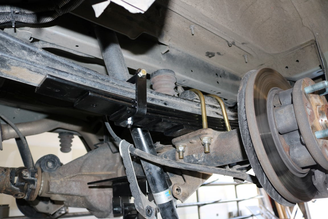 REAR 5 LEAF MINI SPRING PACK - TRANSIT (2015+ SINGLE REAR WHEEL) by VAN COMPASS: Close-up of the spring pack's metal components, showcasing detailed engineering and installation parts.