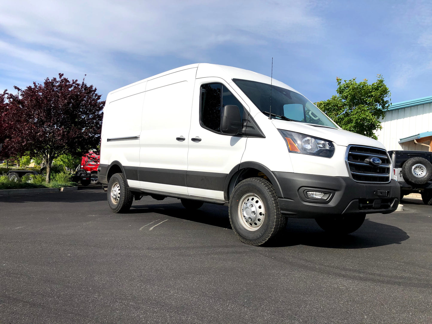 TOPO 2.0 FRONT AND REAR LIFT KIT - TRANSIT (2015-PRESENT) by VAN COMPASS installed on a white van, highlighting suspension components and improved ride height.