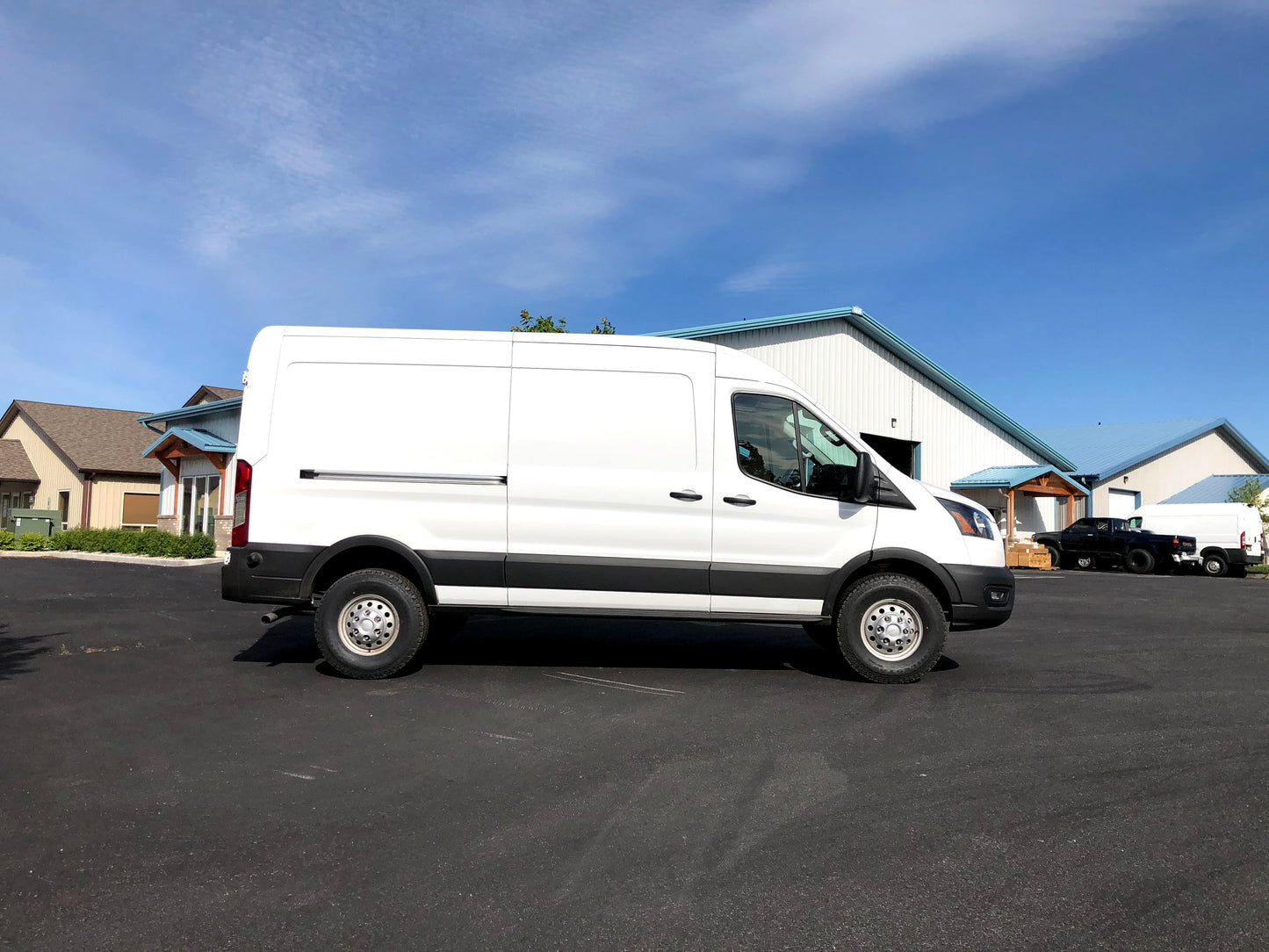 Van Compass TOPO 2.0 front and rear lift kit for Ford Transit (2015-present) installed on a white van in a parking lot.