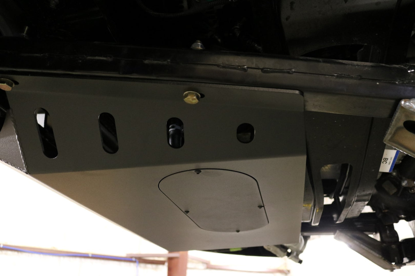ALUMINUM INTERCOOLER SKID PLATE - TRANSIT (2015+) by VAN COMPASS: A metal skid plate with multiple holes designed for engine protection in Ford Transit vans.