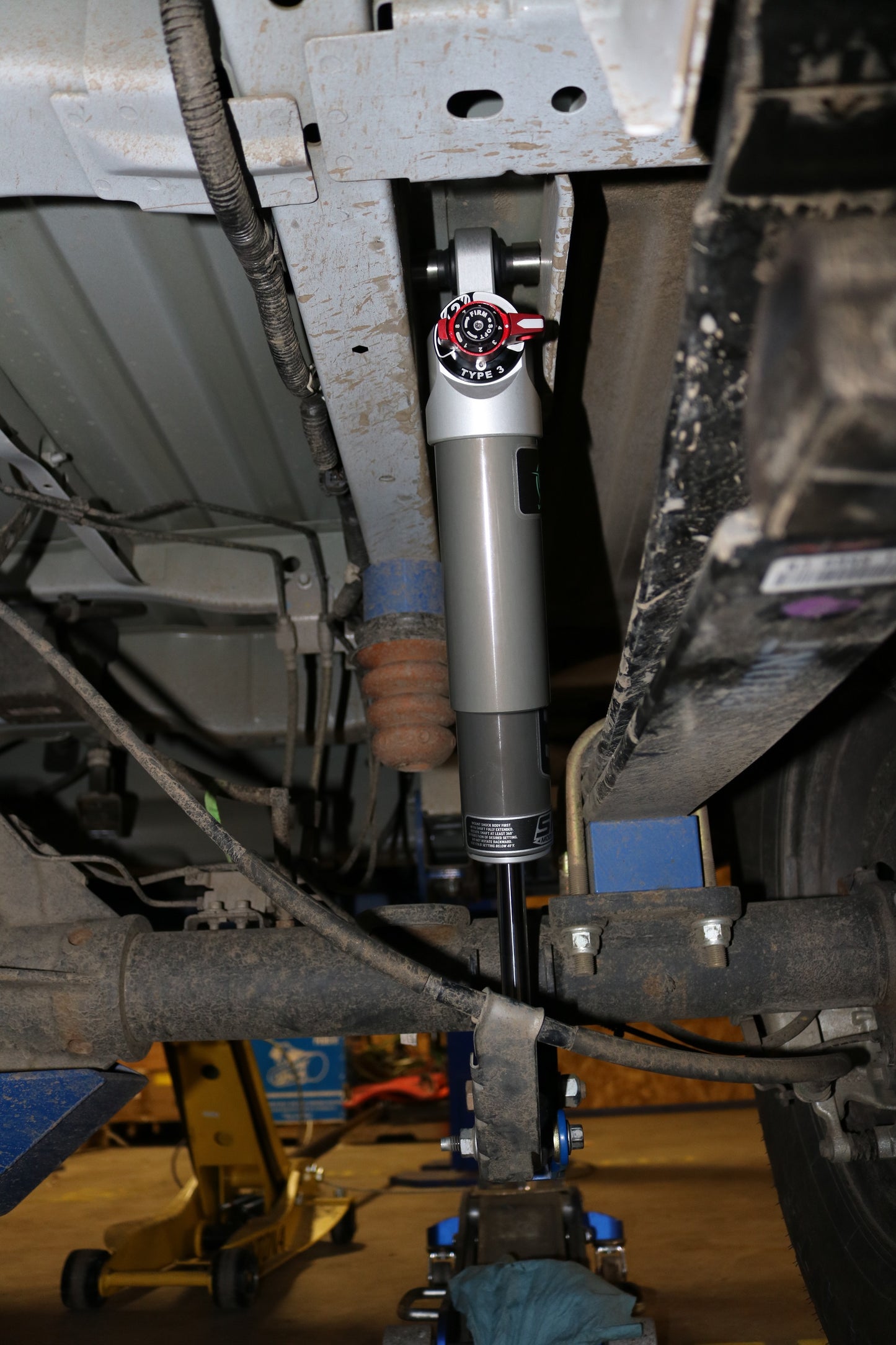 FALCON 3.3 SP2 Fast Adjust Rear Shocks - Transit (2013+), close-up view showcasing the silver knob and metal components under the vehicle, highlighting engineering precision.