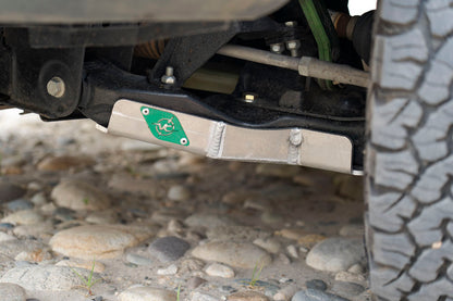 FRONT LOWER CONTROL ARM SKIDPLATES - SPRINTER (2007+) by VAN COMPASS, showing a metal frame with a green logo, tire, and tig-welded aluminum skid plates.