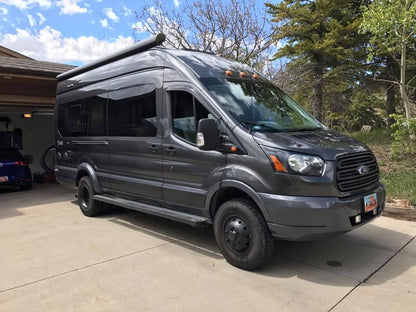 TERRAIN 2 REAR LIFT KIT - TRANSIT (2015+) by VAN COMPASS installed on a grey van parked in a driveway, showcasing enhanced suspension and ground clearance.