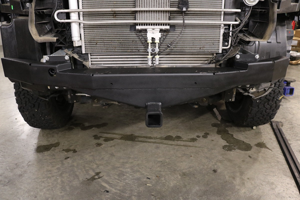 Front Receiver Hitch for Sprinter (2015+) by Van Compass, showcasing close-up details of the hitch mechanism, including the radiator and tire, demonstrating its robust construction.