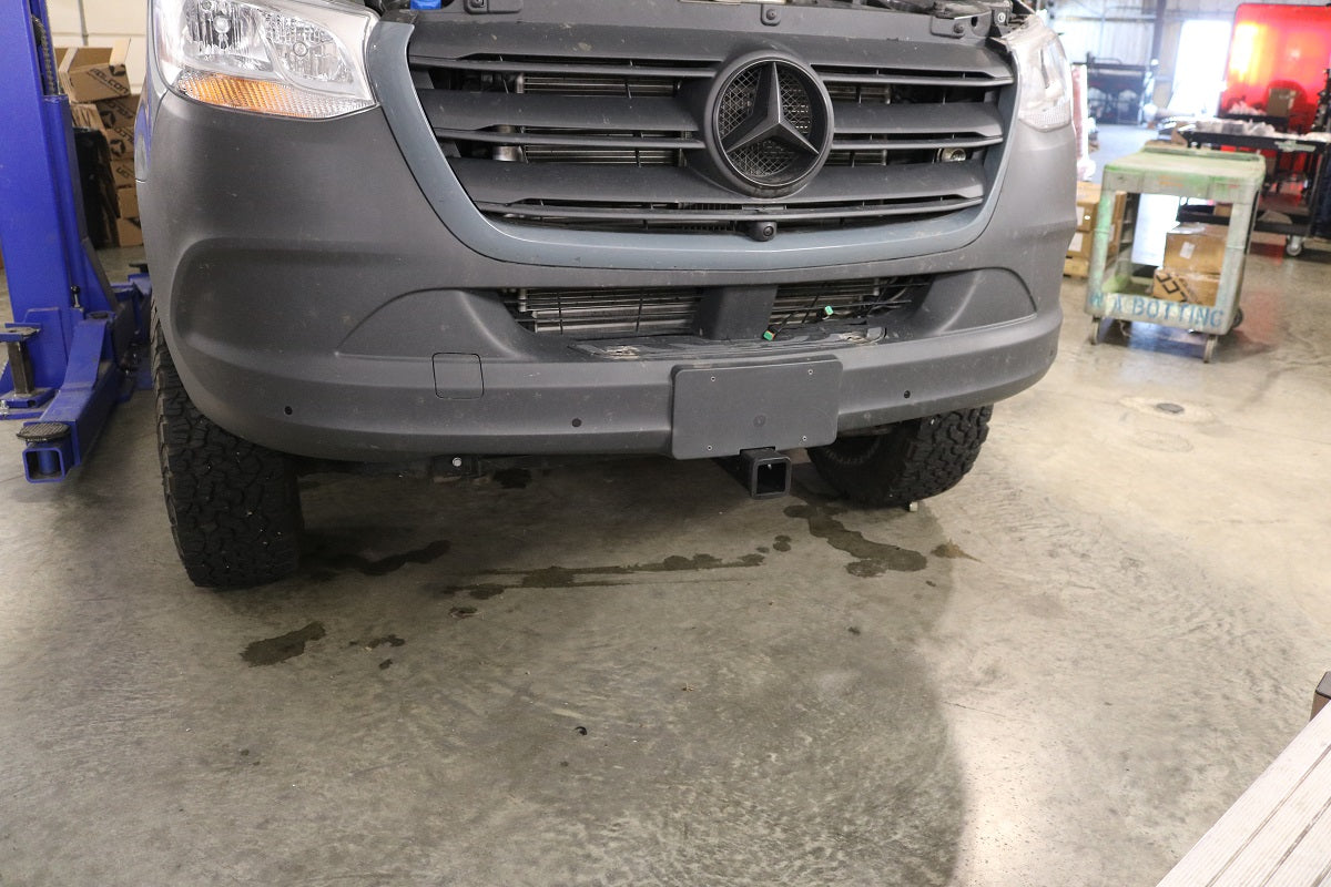 Front view of a vehicle showcasing the FRONT RECEIVER HITCH - SPRINTER (2015+) by VAN COMPASS, highlighting the front bumper and grille.