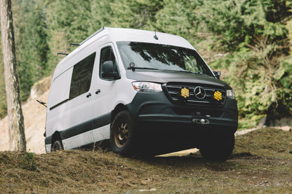 White van on dirt road showcasing the STRIKER 2 Lift Kit (Front Only) - Sprinter 2WD (2019-2022) by Van Compass, enhancing ground clearance for off-road adventures.